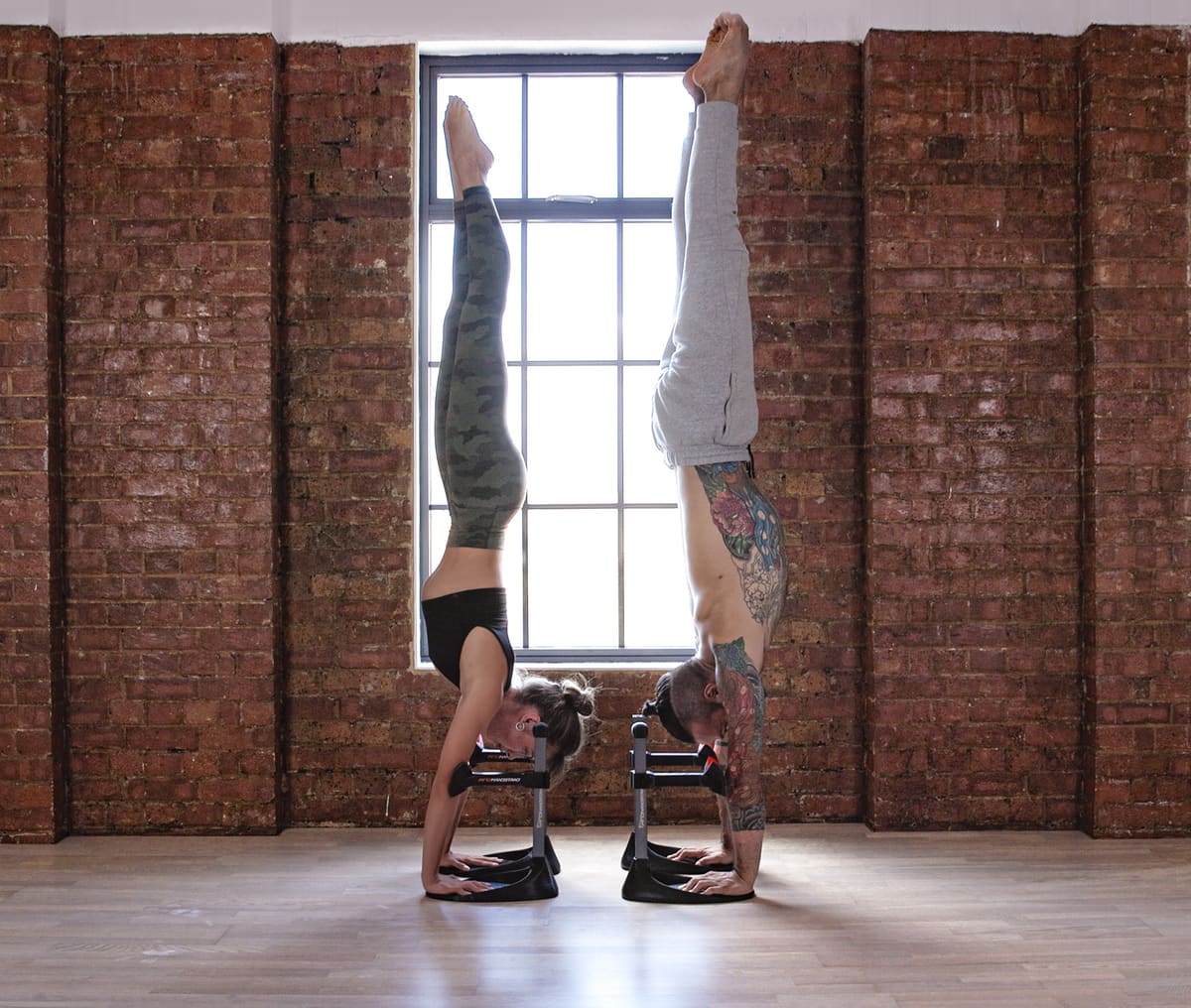 Two athletes holding a handstand on ProHandstand devices